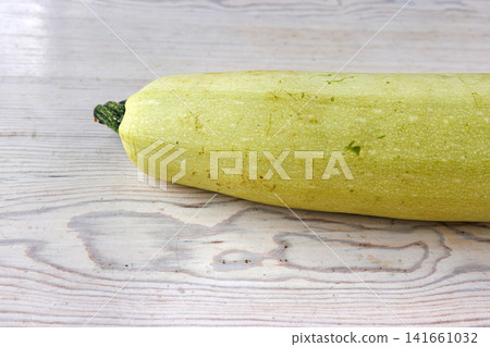 Whole pale green zucchini on light wooden table. Minimal composition. Selective focus Whole pale green zucchini on light wooden table. Minimal composition. Selective focus 141661032