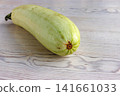Whole pale green zucchini on light wooden table. Minimal composition. Selective focus Whole pale green zucchini on light wooden table. Minimal composition. Selective focus 141661033