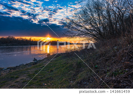 Vistula River near Warsaw at dusk with sunset and bare riverside trees Vistula River near Warsaw at dusk with sunset and bare riverside trees 141661459