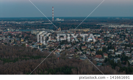 Aerial dusk view of Warsaw suburbs with red and white smokestack Aerial dusk view of Warsaw suburbs with red and white smokestack 141661691