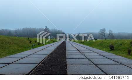 Foggy memorial walkway leading to a dark statue in Belarus Foggy memorial walkway leading to a dark statue in Belarus 141661745