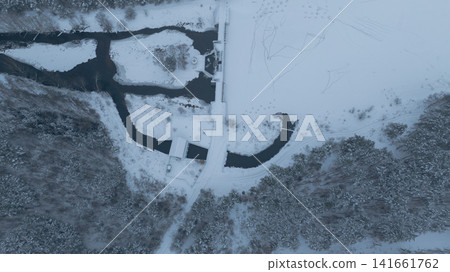 Aerial winter view of Belarus river, dam, frozen reservoir, pine woods Aerial winter view of Belarus river, dam, frozen reservoir, pine woods 141661762