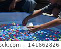 Children enjoying scooping up super balls at a festival stall. 141662826