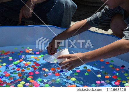 Children enjoying scooping up super balls at a festival stall. Children enjoying scooping up super balls at a festival stall. 141662826