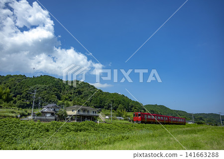 一列紅色的本地火車在夏天的天空下行駛。 141663288