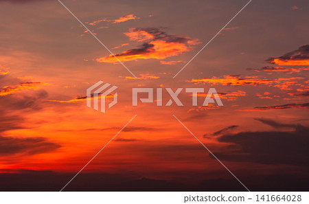 Orange and red sunset sky with glowing clouds, dramatic evening atmosphere and colorful cloudscape background. Warm natural weather scene. Nature and background design. Orange and crimson clouds. 141664028