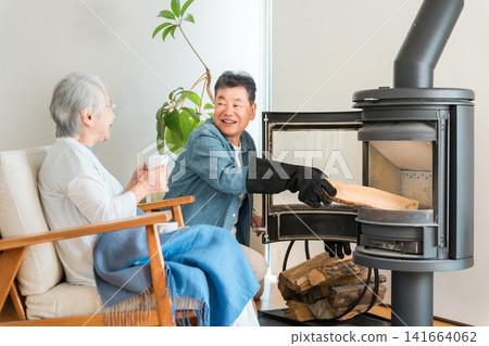 A senior couple chatting happily in the living room of their home, which has a wood-burning stove. A senior couple chatting happily in the living room of their home, which has a wood-burning stove. 141664062