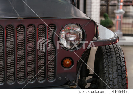 A close-up photograph highlights the headlight and grille of a classic utility vehicle. The image captures rugged construction and timeless automotive styling. A close-up photograph highlights the headlight and grille of a classic utility vehicle. The image captures rugged construction and timeless automotive styling. 141664453