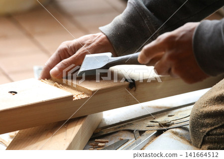 A man cutting wood with a chisel A man cutting wood with a chisel 141664512