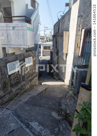 在陽光明媚的城市後巷裡,房子的影子投射在道路上。 在陽光明媚的城市後巷裡,房子的影子投射在道路上。 141664518