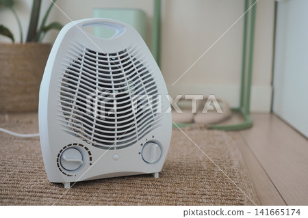 Small white room heater on the floor in a cozy space Small white room heater on the floor in a cozy space 141665174