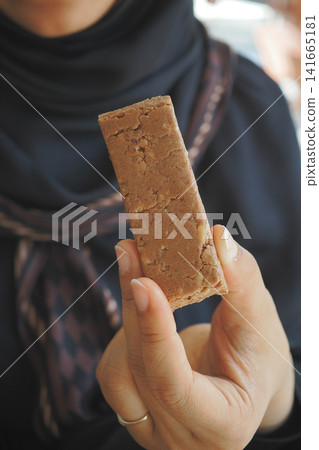 Holding a sweet treat in hand during a gathering Holding a sweet treat in hand during a gathering 141665181