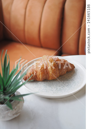 Croissant on a plate in a cafe setting Croissant on a plate in a cafe setting 141665186