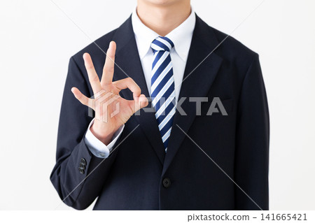 A young businessman in a suit making a circular pose. A young businessman in a suit making a circular pose. 141665421