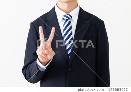 一位身穿西裝的年輕商人比出和平手勢。 一位身穿西裝的年輕商人比出和平手勢。 141665422