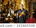 The head priest delivers a sermon at an altar adorned with a portrait of the deceased and an urn. The head priest delivers a sermon at an altar adorned with a portrait of the deceased and an urn. 141665506
