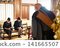 Women in mourning attire bow deeply before a Buddhist monk. Women in mourning attire bow deeply before a Buddhist monk. 141665507