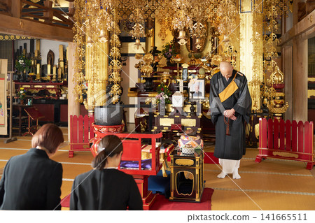 在追悼儀式上,首席祭司向死者家屬鞠躬致意。 在追悼儀式上,首席祭司向死者家屬鞠躬致意。 141665511