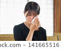 A young woman in mourning clothes wipes away tears with a handkerchief. A young woman in mourning clothes wipes away tears with a handkerchief. 141665516