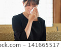 A young woman in mourning clothes wipes away tears with a handkerchief. A young woman in mourning clothes wipes away tears with a handkerchief. 141665517