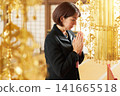 A woman clasps her hands together in prayer, remembering the deceased in the main hall. A woman clasps her hands together in prayer, remembering the deceased in the main hall. 141665518