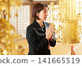 A woman in mourning attire offers prayers at a memorial service. A woman in mourning attire offers prayers at a memorial service. 141665519