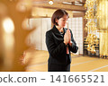 A woman in mourning clothes quietly clasps her hands together in prayer. A woman in mourning clothes quietly clasps her hands together in prayer. 141665521