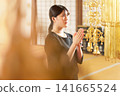 A young woman clasps her hands together in prayer, remembering the deceased in the main hall. A young woman clasps her hands together in prayer, remembering the deceased in the main hall. 141665524