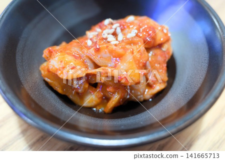 A close-up of napa cabbage kimchi served in a small black bowl. A close-up of napa cabbage kimchi served in a small black bowl. 141665713