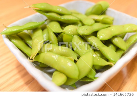 Boiled edamame served in a small bowl - a classic summer snack. Boiled edamame served in a small bowl - a classic summer snack. 141665726