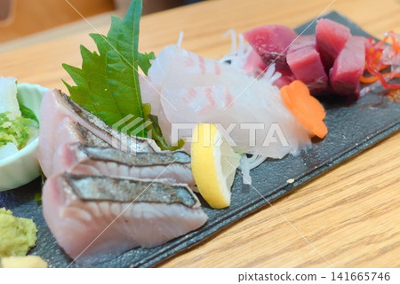 一盤新鮮的生魚片,讓人想起日本餐廳的海鮮料理和日本料理。 一盤新鮮的生魚片,讓人想起日本餐廳的海鮮料理和日本料理。 141665746