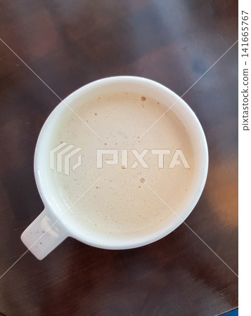 Top view of white coffee cup filled with creamy beverage on wooden table surface Top view of white coffee cup filled with creamy beverage on wooden table surface 141665767