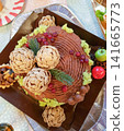 Chocolate cake decorated with pine cone shapes, berries, and green moss on a festive platter 141665773