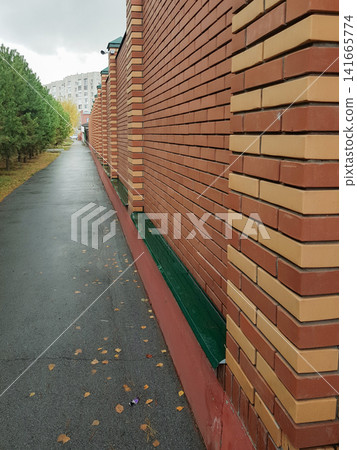 Red brick wall with green ledge along sidewalk in urban area surrounded by trees Red brick wall with green ledge along sidewalk in urban area surrounded by trees 141665774