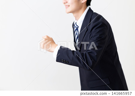 一位身穿西裝的年輕商人擺出跑步的姿勢。 一位身穿西裝的年輕商人擺出跑步的姿勢。 141665957