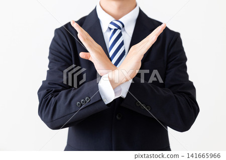 一位身穿西裝的年輕商人用手比劃了一個「X」型。 一位身穿西裝的年輕商人用手比劃了一個「X」型。 141665966