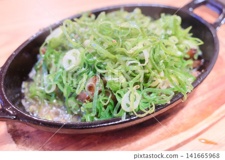 Chicken gizzards topped with green onions: A popular izakaya snack dish served on a hot plate. Chicken gizzards topped with green onions: A popular izakaya snack dish served on a hot plate. 141665968