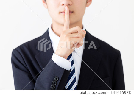 A young businessman in a suit strikes a secretive pose. A young businessman in a suit strikes a secretive pose. 141665978