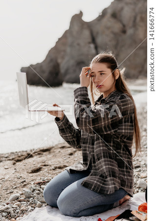 Woman laptop beach sitting on a rocky shore looking worried while holding her computer to work remotely 141666774