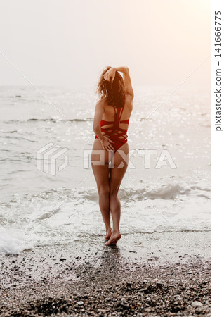 Woman beach swimsuit standing on a pebble shore facing the sea with sunlight enjoying summer vacation and relaxation Woman beach swimsuit standing on a pebble shore facing the sea with sunlight enjoying summer vacation and relaxation 141666775