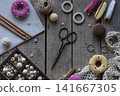 Handmade sewing and knitting workspace with colorful pincushions embroidery hoop lace scissors yarn and crochet accessories on wooden background flat lay style 141667305