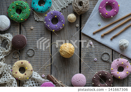 Handmade knitting and sewing frame composition with colorful donut pincushions yarn scissors lace and embroidery accessories on wooden table flat lay Handmade knitting and sewing frame composition with colorful donut pincushions yarn scissors lace and embroidery accessories on wooden table flat lay 141667306