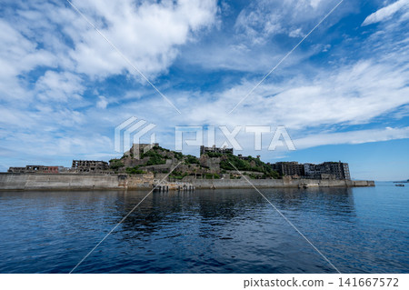 A panoramic view of Hashima Island (Battleship Island) standing under a blue sky. A panoramic view of Hashima Island (Battleship Island) standing under a blue sky. 141667572