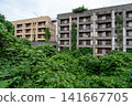 The deserted apartment buildings on Ikeshima Island stand tall in the depths of overgrown weeds. 141667705