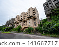 A massive cluster of abandoned high-rise apartment buildings stands beside the road on Ikeshima Island. 141667717
