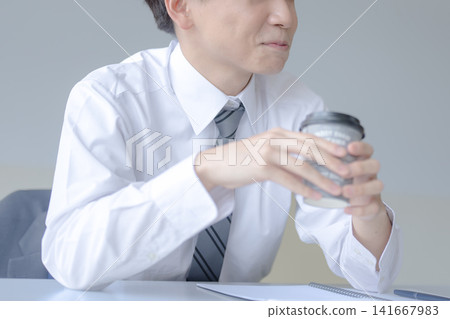 一位商人手拿咖啡杯,這是他休息時的照片。 一位商人手拿咖啡杯,這是他休息時的照片。 141667983