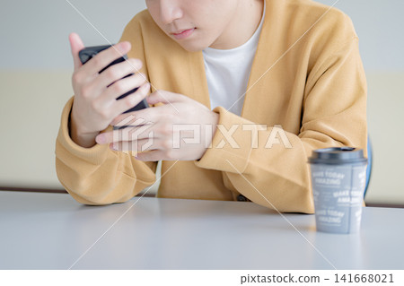 一個男人全神貫注地盯著他的智慧型手機,這展現了一個有空閒時間的人的形象。 一個男人全神貫注地盯著他的智慧型手機,這展現了一個有空閒時間的人的形象。 141668021