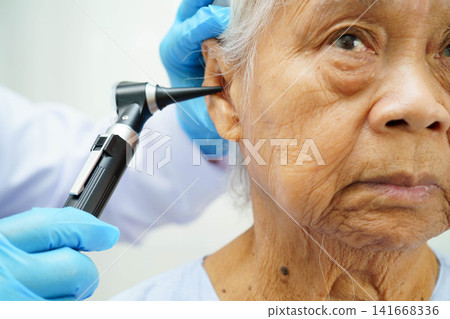 Otolaryngologist or ENT physician doctor examining senior patient ear with otoscope, hearing loss problem. Otolaryngologist or ENT physician doctor examining senior patient ear with otoscope, hearing loss problem. 141668336