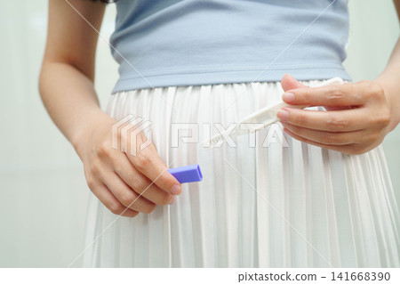 Asian holding pregnancy test for female of ovulation day, fetus, maternity, childbirth, birth control. Asian holding pregnancy test for female of ovulation day, fetus, maternity, childbirth, birth control. 141668390