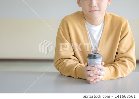 一位男士手捧咖啡杯,悠閒地享受著咖啡館時光,這是典型的咖啡館場景。 一位男士手捧咖啡杯,悠閒地享受著咖啡館時光,這是典型的咖啡館場景。 141668561